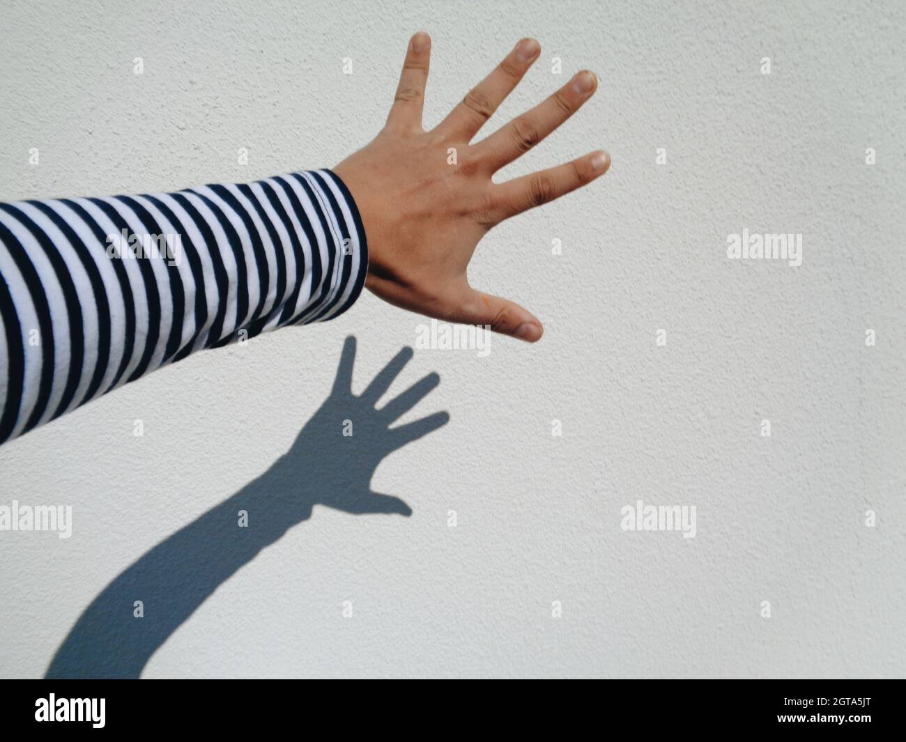 Shadow Of Person Hand On Wall Stock Photo