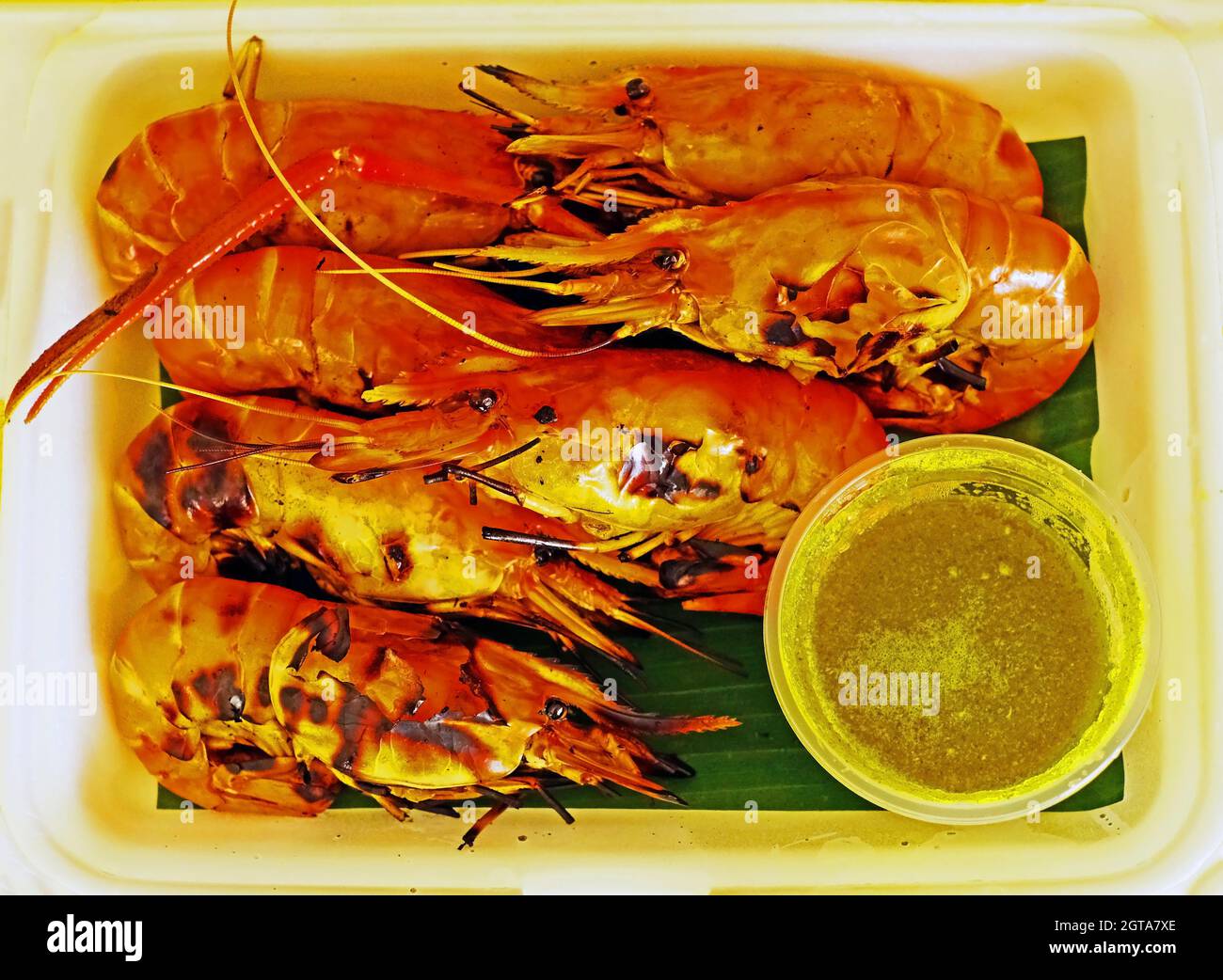 Grilled lobsters with spicy sauce on banana leaf and white foam plate