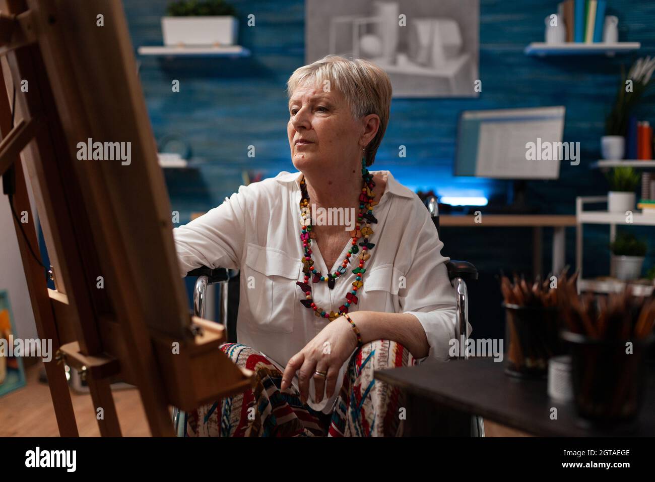 Portrait of disabled old artist sitting in artwork studio at home ...