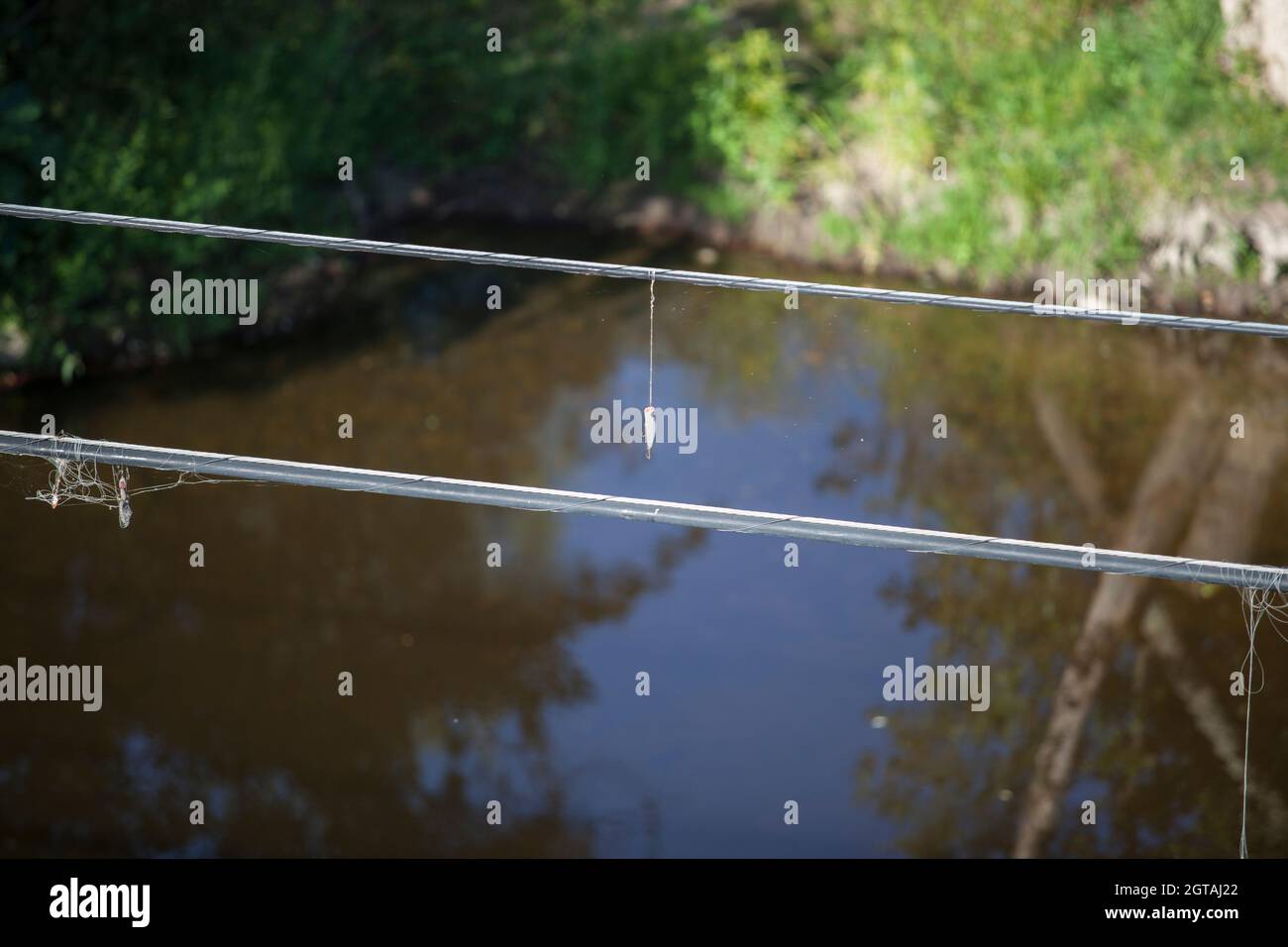 Some spoon lures tangled at electrical wire above the river. Selective focus Stock Photo