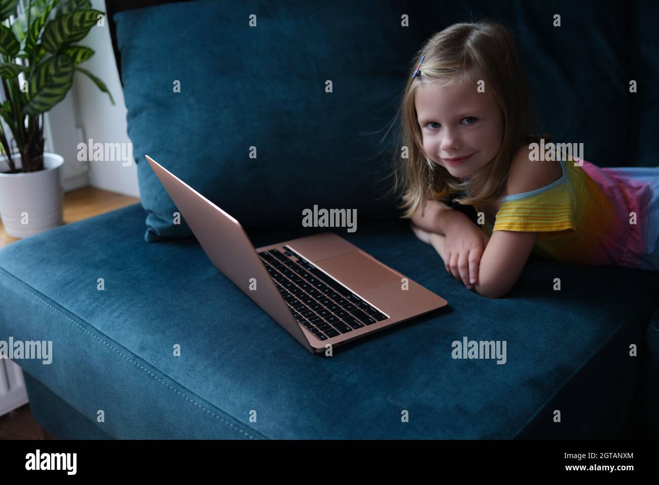 Little smiling girl lies on couch with laptop closeup Stock Photo - Alamy