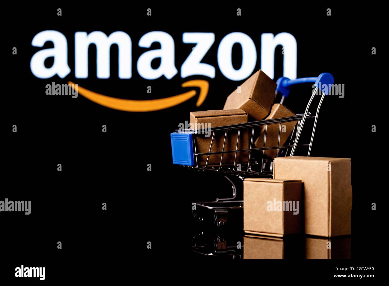 Shopping cart with parcels on the black background with Amazon logo. Stock Photo