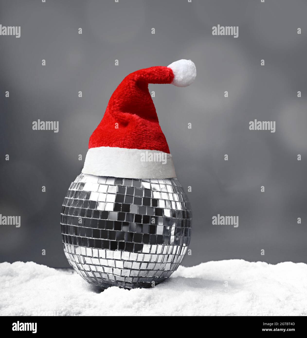 Beautiful mirrored Christmas ball on snow on grey background. Stock Photo