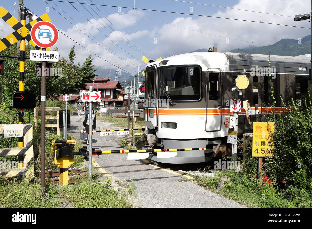 Iida, Nagano, Japan, 20211609 , Rail crossing with a train slowly