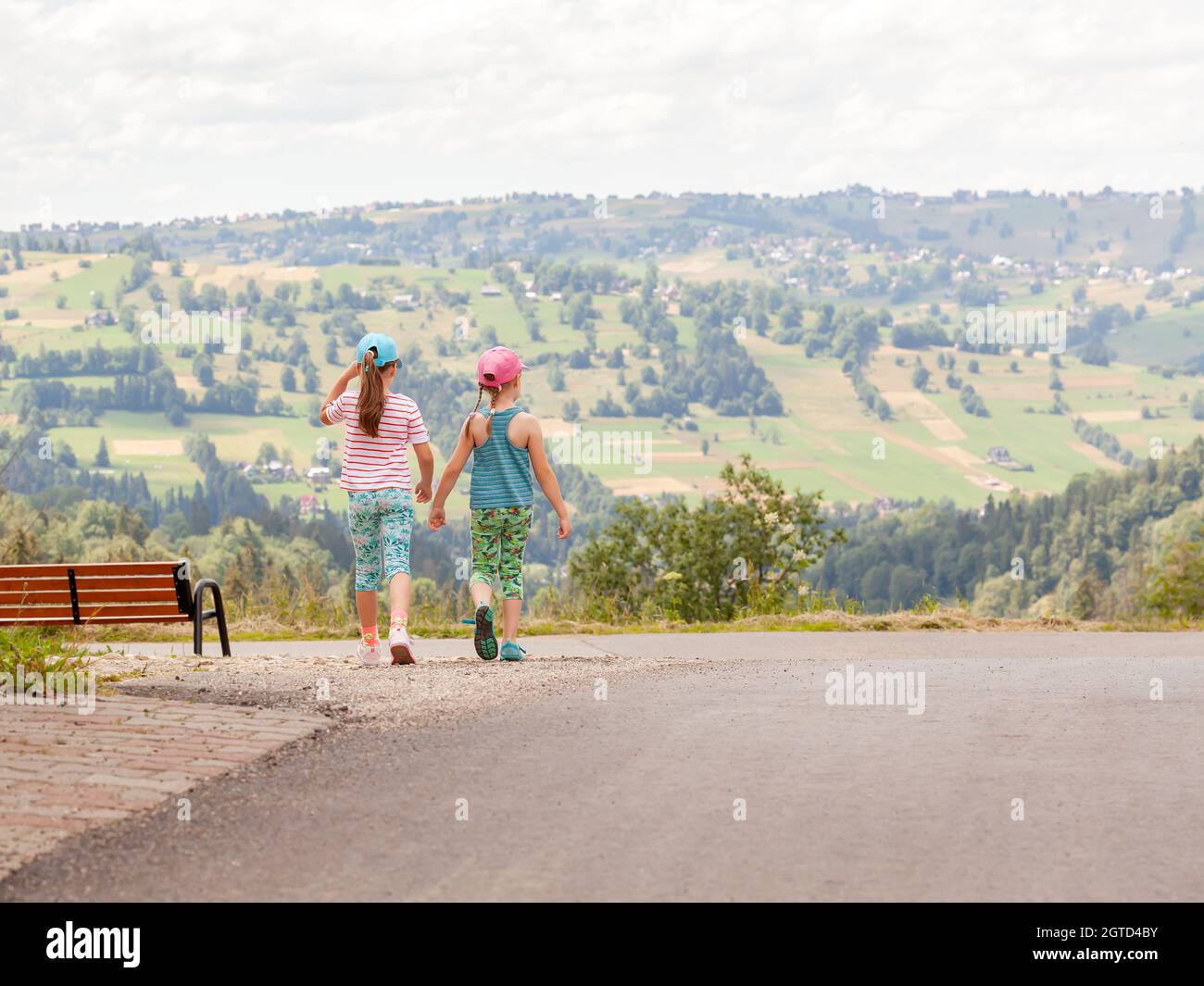 Two girls exploring, young kids walking down the road together ...