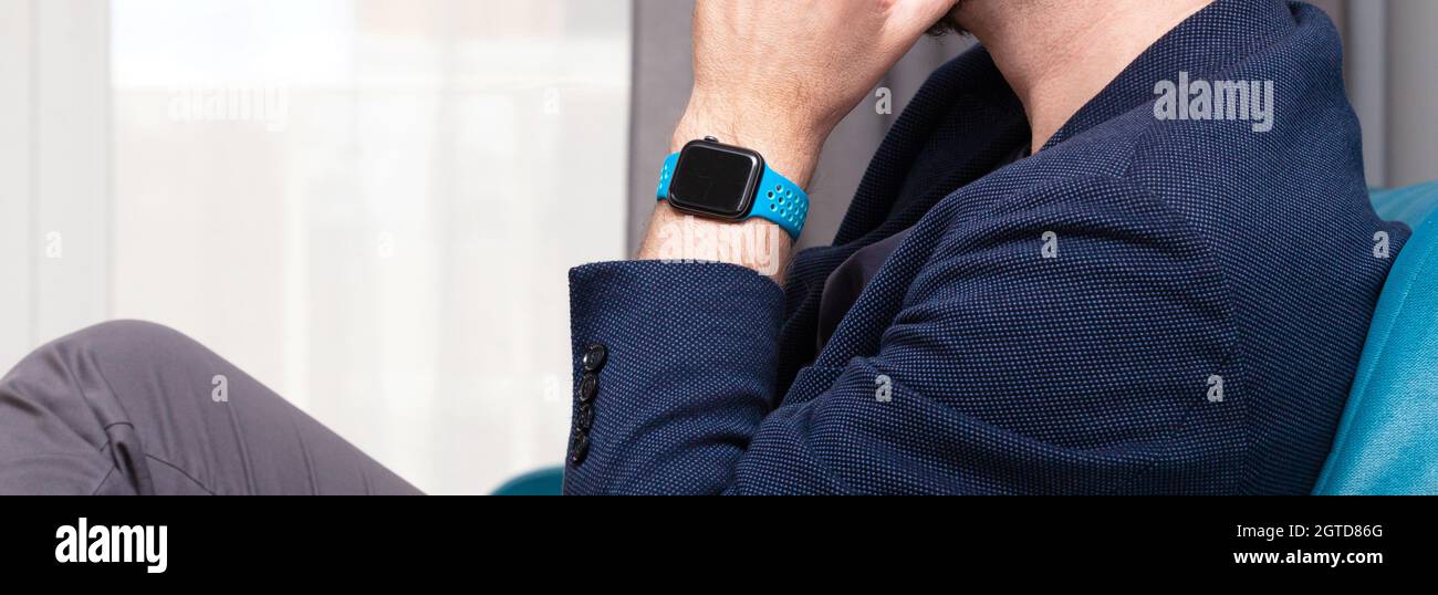 Anonymous unrecognizable man wearing an Apple Watch on his wrist wide shot, closeup, hand under chin. Apple company, iOS system, personal gadgets, acc Stock Photo