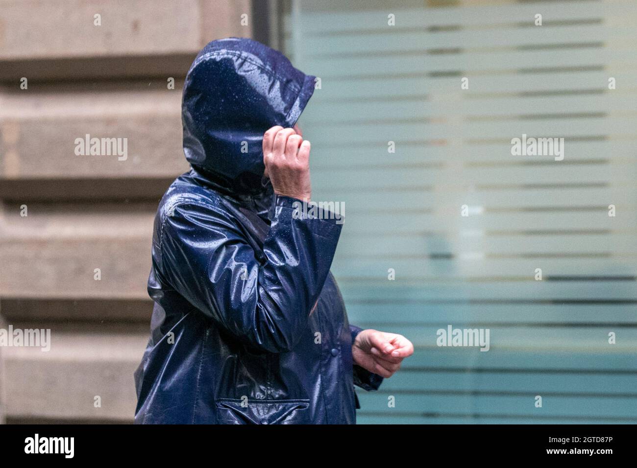 Keep hair dry in Southport, Lancashire.  UK Weather. 02 Oct 2021. Strong winds and heavy showers in the town centre.    Credit: MediaWorldImages/AlamyLiveNews Stock Photo