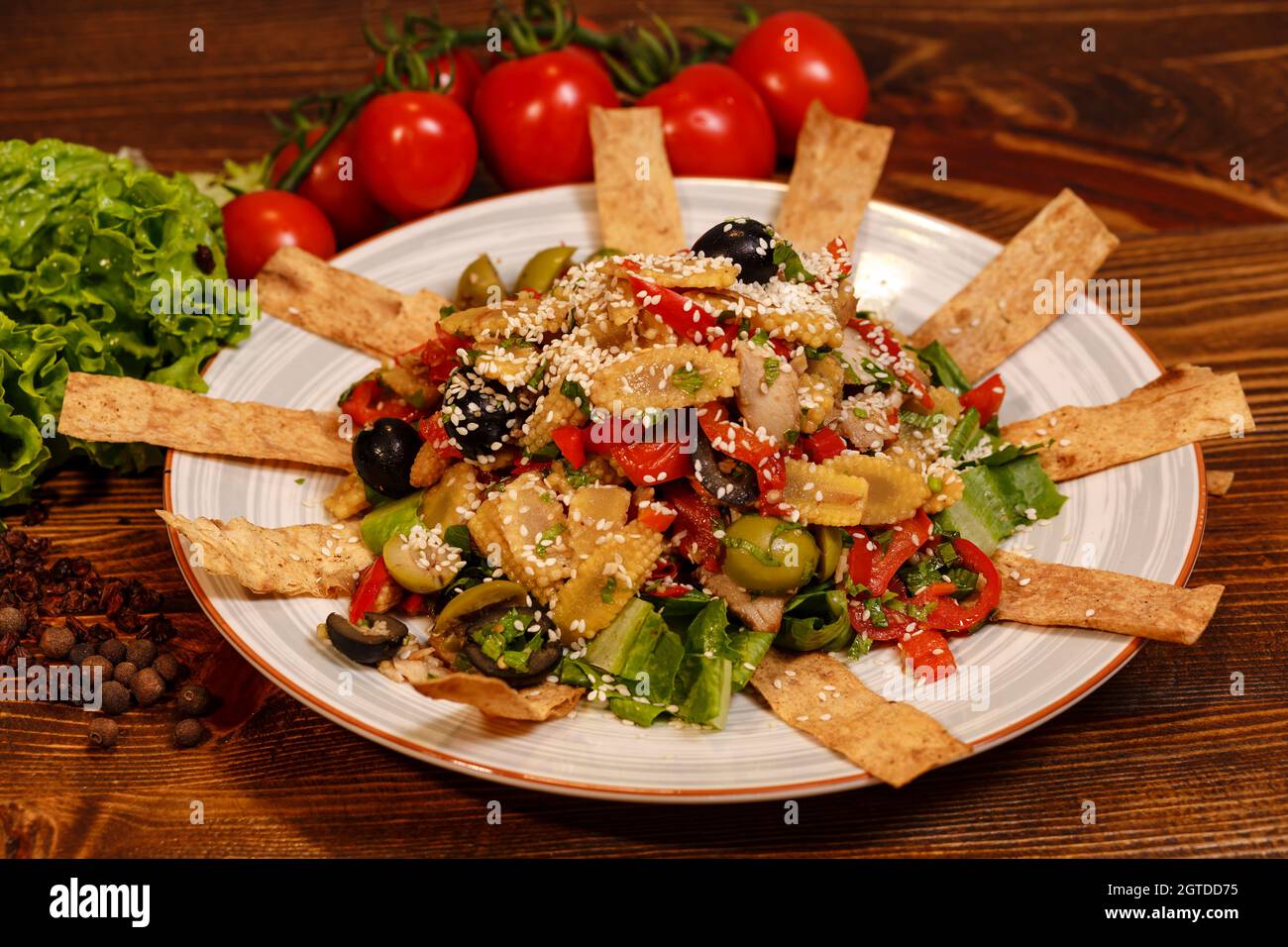 Tasty salad in plate with olives, marinated baby corns, meat, pepper and other ingredients. Stock Photo