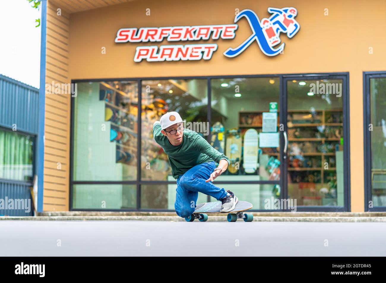 Asian Cheerful man playing surfskate or skateboard in front turn action over the surfskate planet x store sop at bangkok, Thailand  extream sport, hea Stock Photo