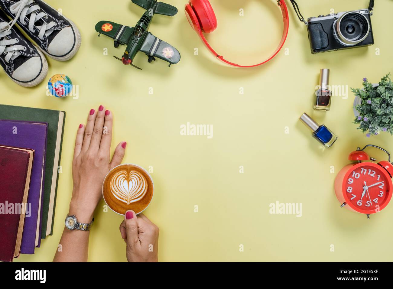 Yellow Wooden Table With Woman Hands Holding Cup Of Coffee,headphone,camera And Alot Of Thing. Stock Photo