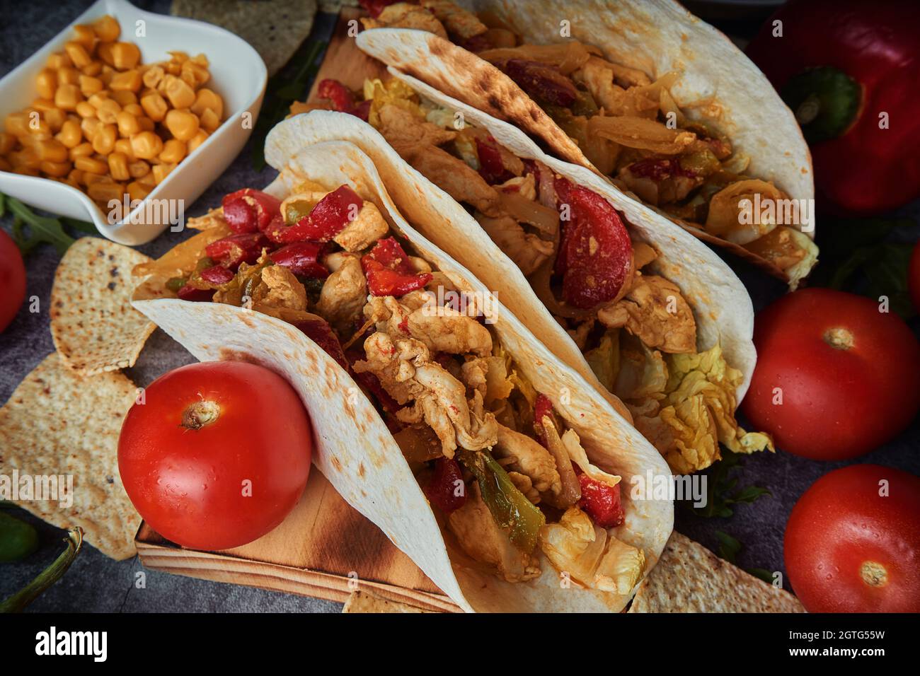 Still Life Of Three Fajitas Or Mexican Tacos With Meat, Pepper, Tomato, Spicy Pepper And Nachos Stock Photo