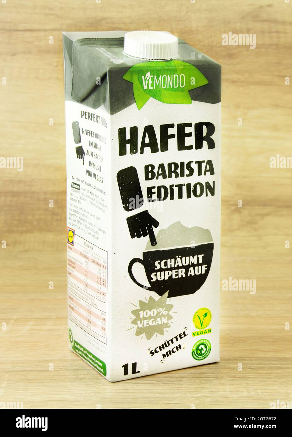 Oatly vegan oat drink Barista Edition in glass with carton behind and oats  strewn around on black background. Editorial use only Stock Photo - Alamy