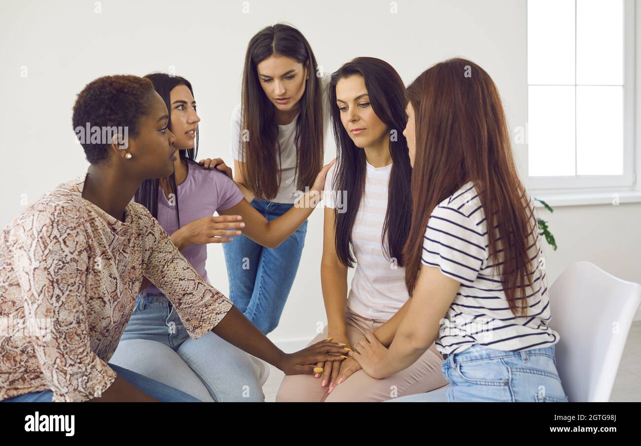 Group of women comforting depressed friend, talking about her problems and supporting her Stock Photo