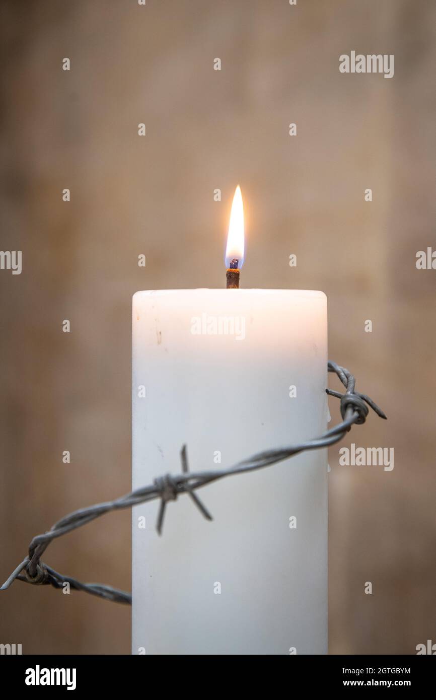 Lit white candle with barb wire Stock Photo