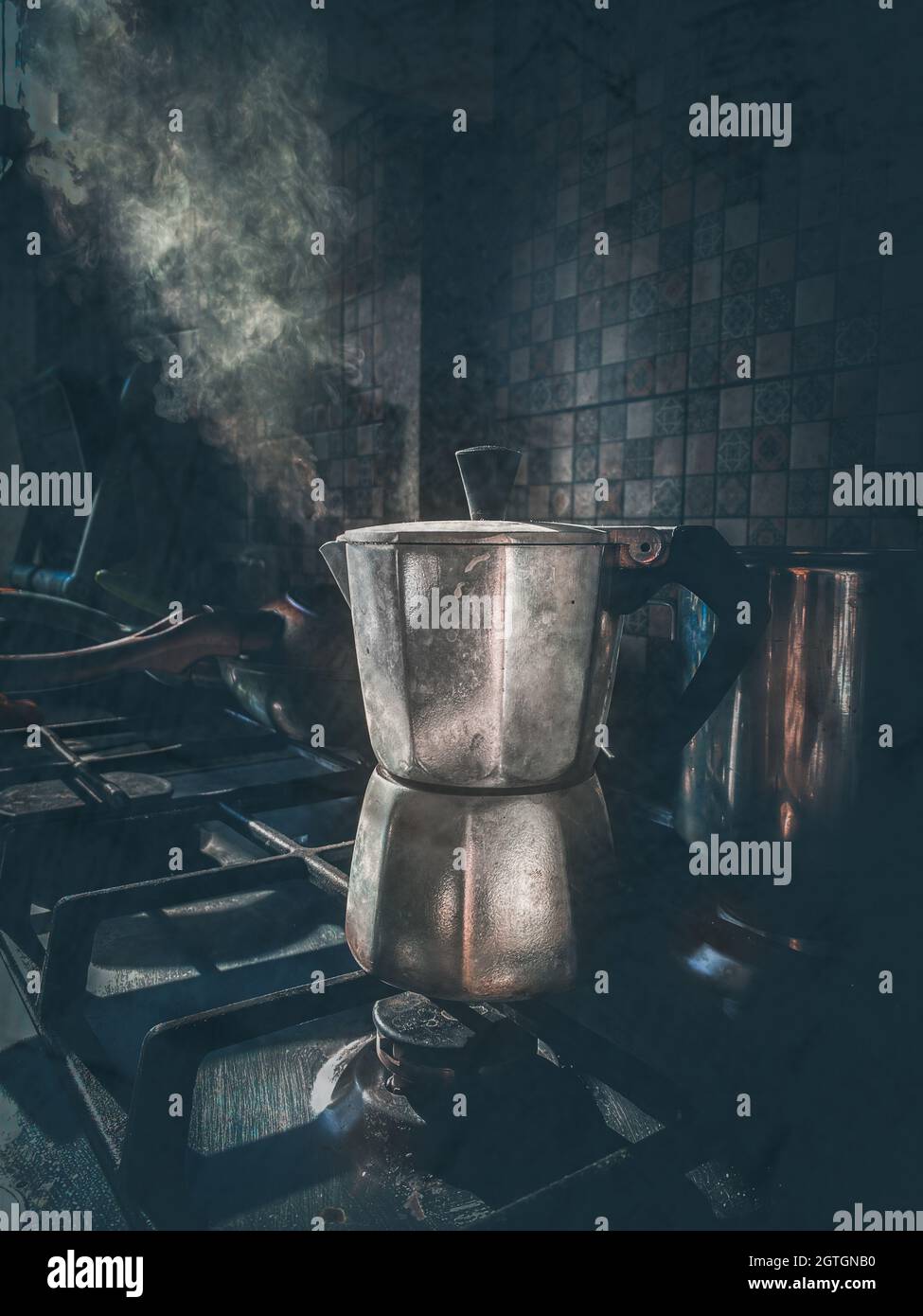Coffeemaker with coffee boils and emits steam on the gascooker. Natural shot in low key. Stock Photo