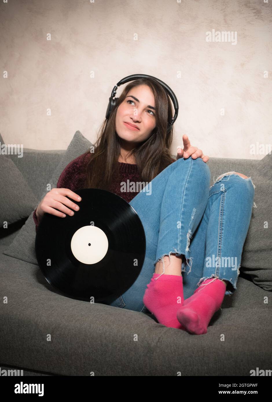 Smiling Young Woman With Record Sitting On Sofa At Home Stock Photo