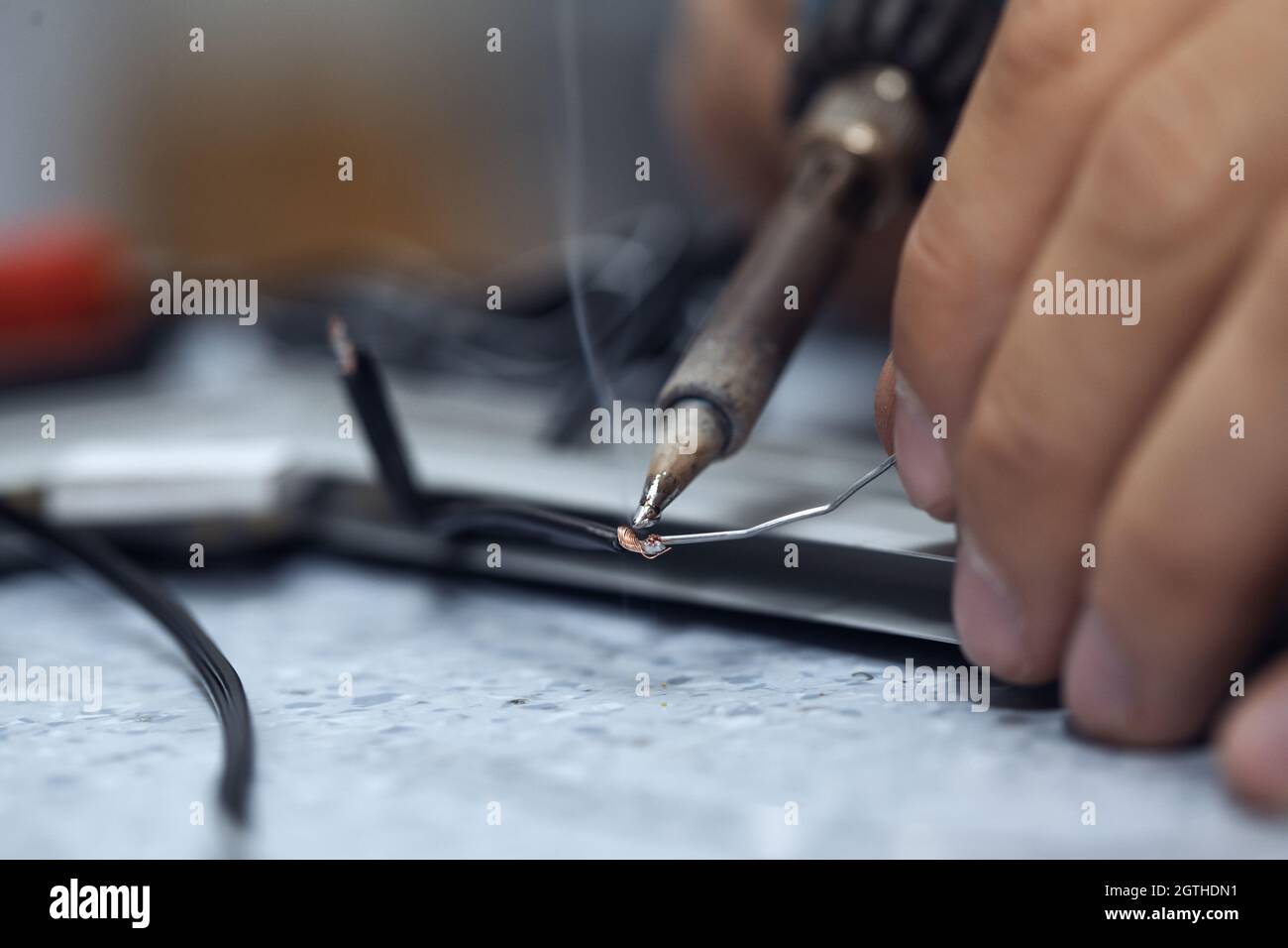 Wires being soldered together with a soldering iron. Melting solder