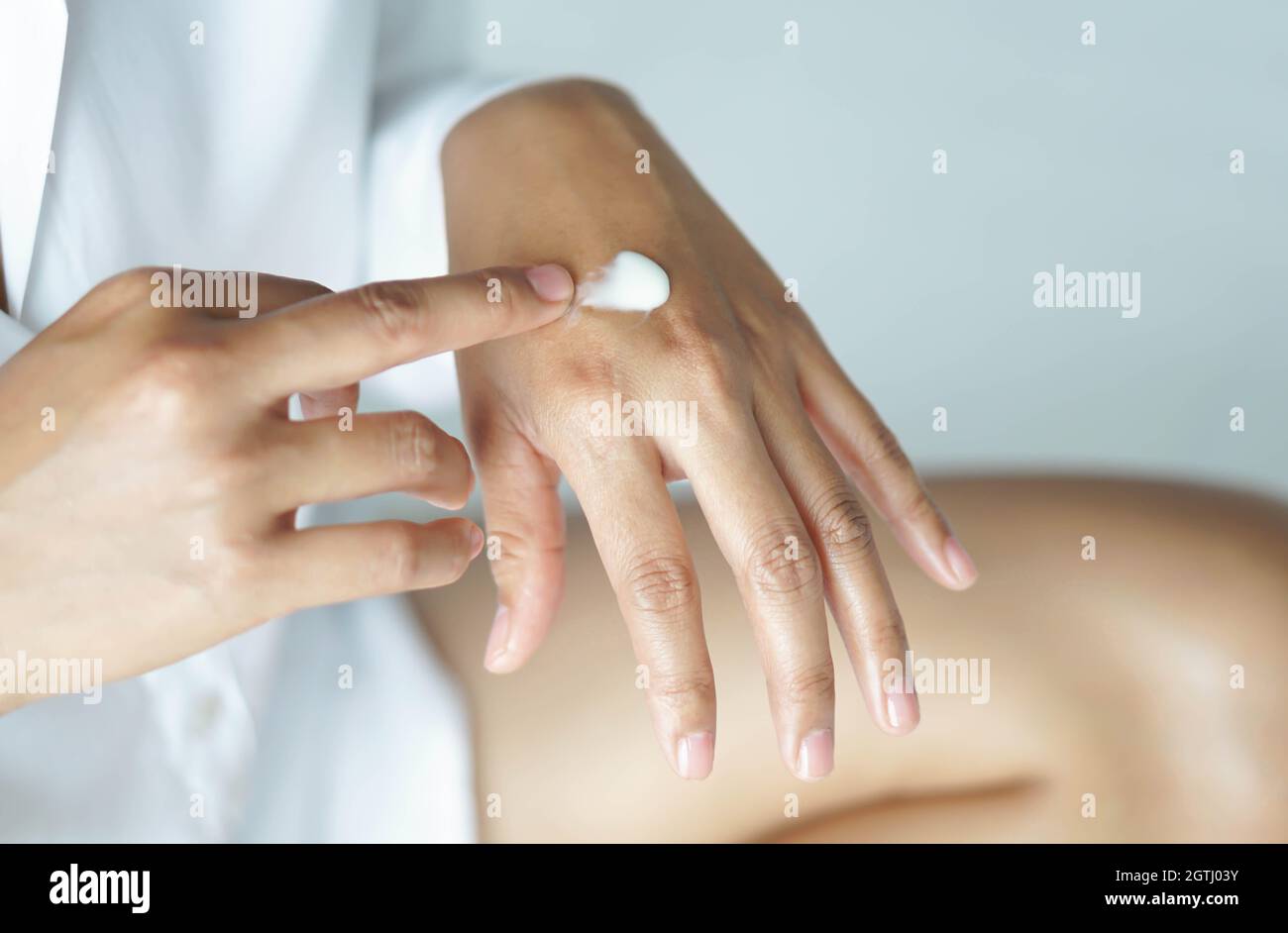 Midsection Of Woman Applying Moisturizer Stock Photo