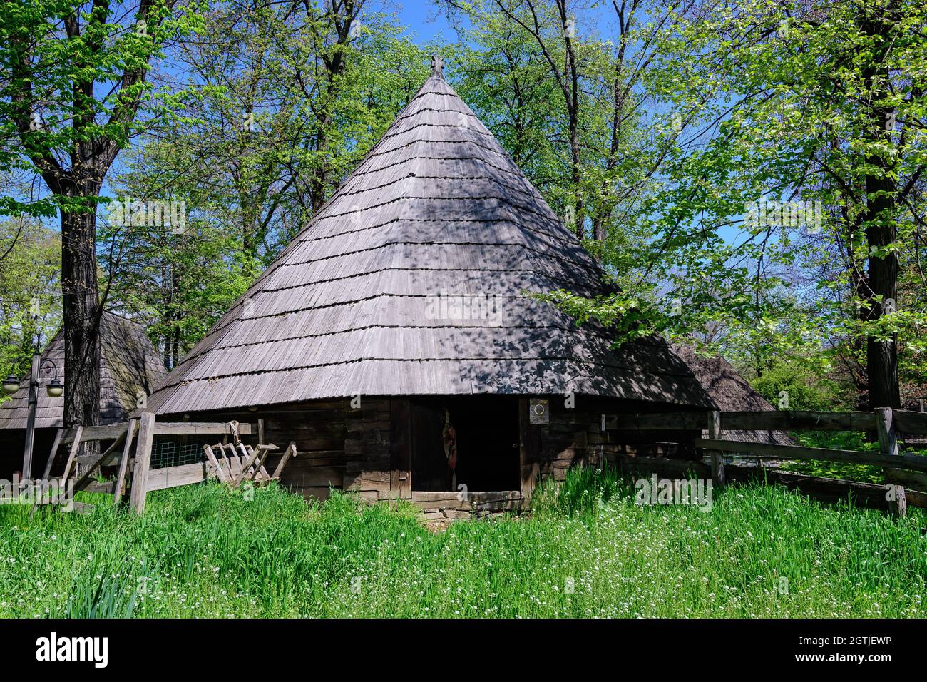 Bucharest, Romania - 25 April 2021: Old traditional Romanian house surounded with many old trees and green grass in Dimitrie Gusti National Village Mu Stock Photo