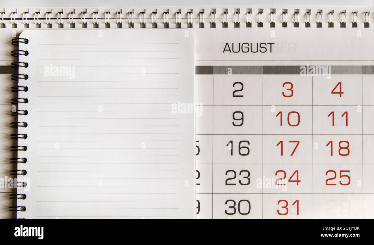 Top View Of An August Paper Calendar And A Blank Page Of A Spiral-bound Notebook Stock Photo