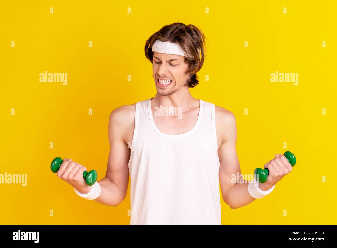 Portrait of attractive weak sportive guy lifting weight working out ...