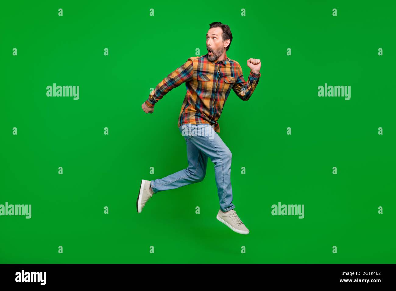 Full length body size view of attractive funky amazed man jumping running away isolated over bright green color background Stock Photo