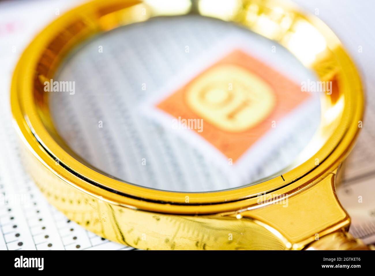 High Angle View Of Golden Magnifying Glass On Paper Stock Photo
