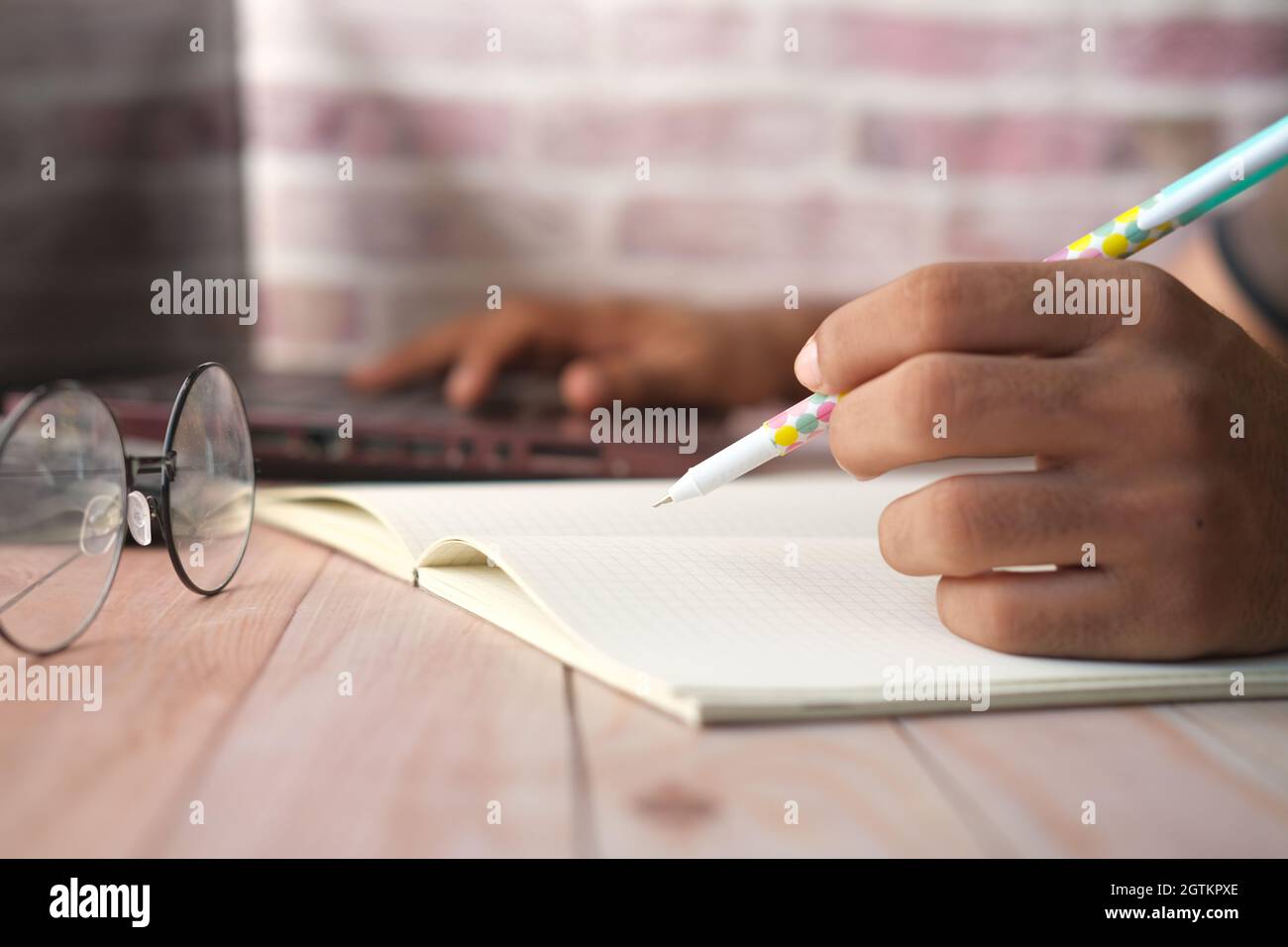 man hand writing on notepad and using laptop  Stock Photo