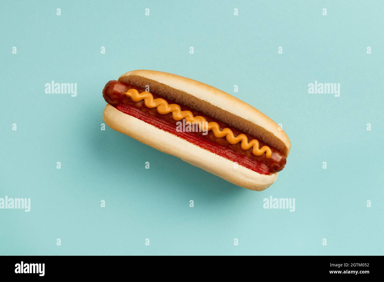 Classic hot dog with wurst, ketchup and mustard on blue background