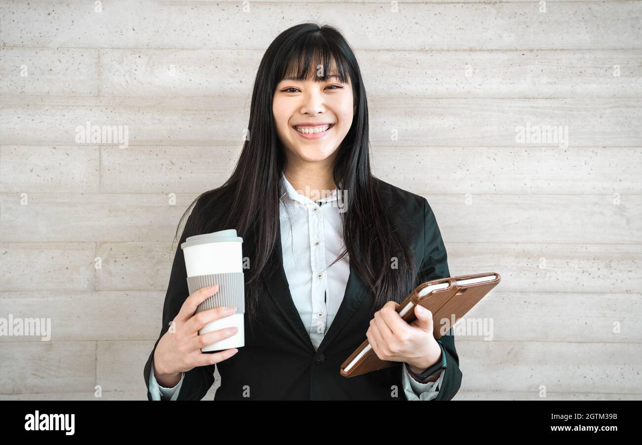 Asian business woman holding smart tablet and take away coffee outside office - Youth entrepreneur concept Stock Photo
