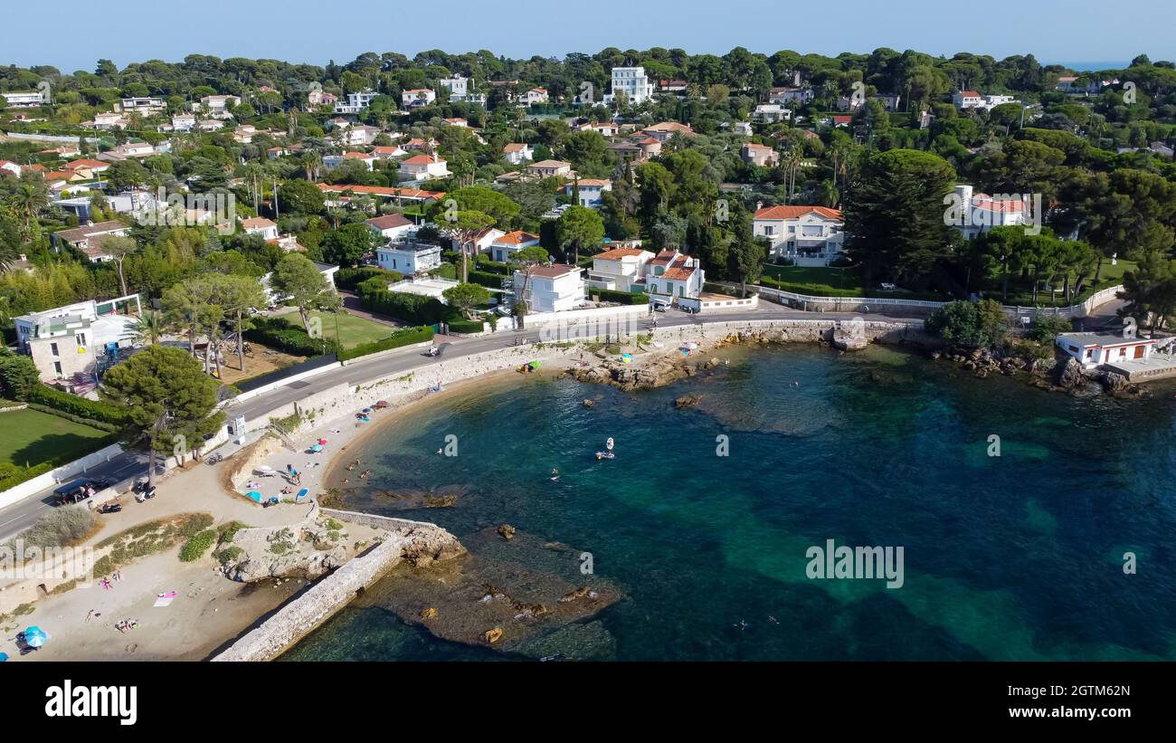 Aerial view of expensive estates behind Mallet Beach on the Cap d'Antibes in the French Riviera - Tourists sunbathing by the Mediterranean Sea in the Stock Photo