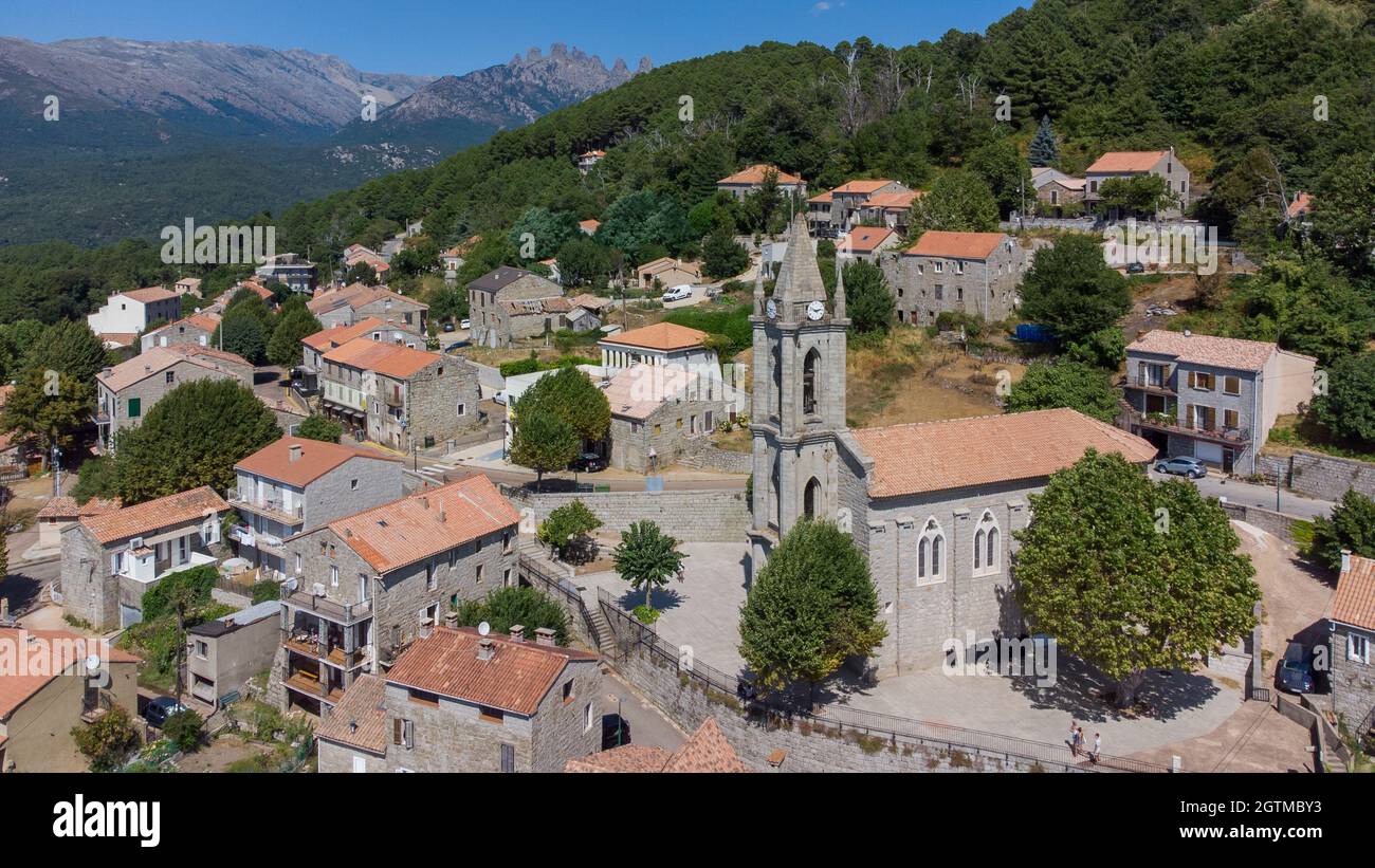 Aerial view of the Parish church of the Assumption in the mountainous village of Zonza in the South of Corsica with the Peaks of Bavella Stock Photo