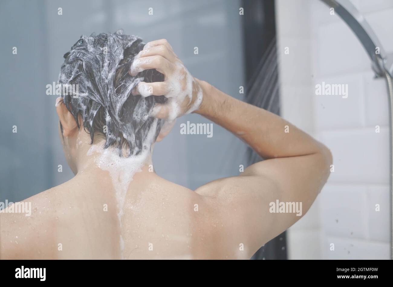 Rear View Of Shirtless Man Bathing In Bathroom At Home Stock Photo