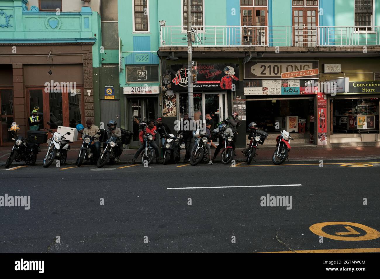 Fast food delivery drivers and their motorcycles parked on the side of the very popular Long street in Cape Town CBD, South Africa. Stock Photo