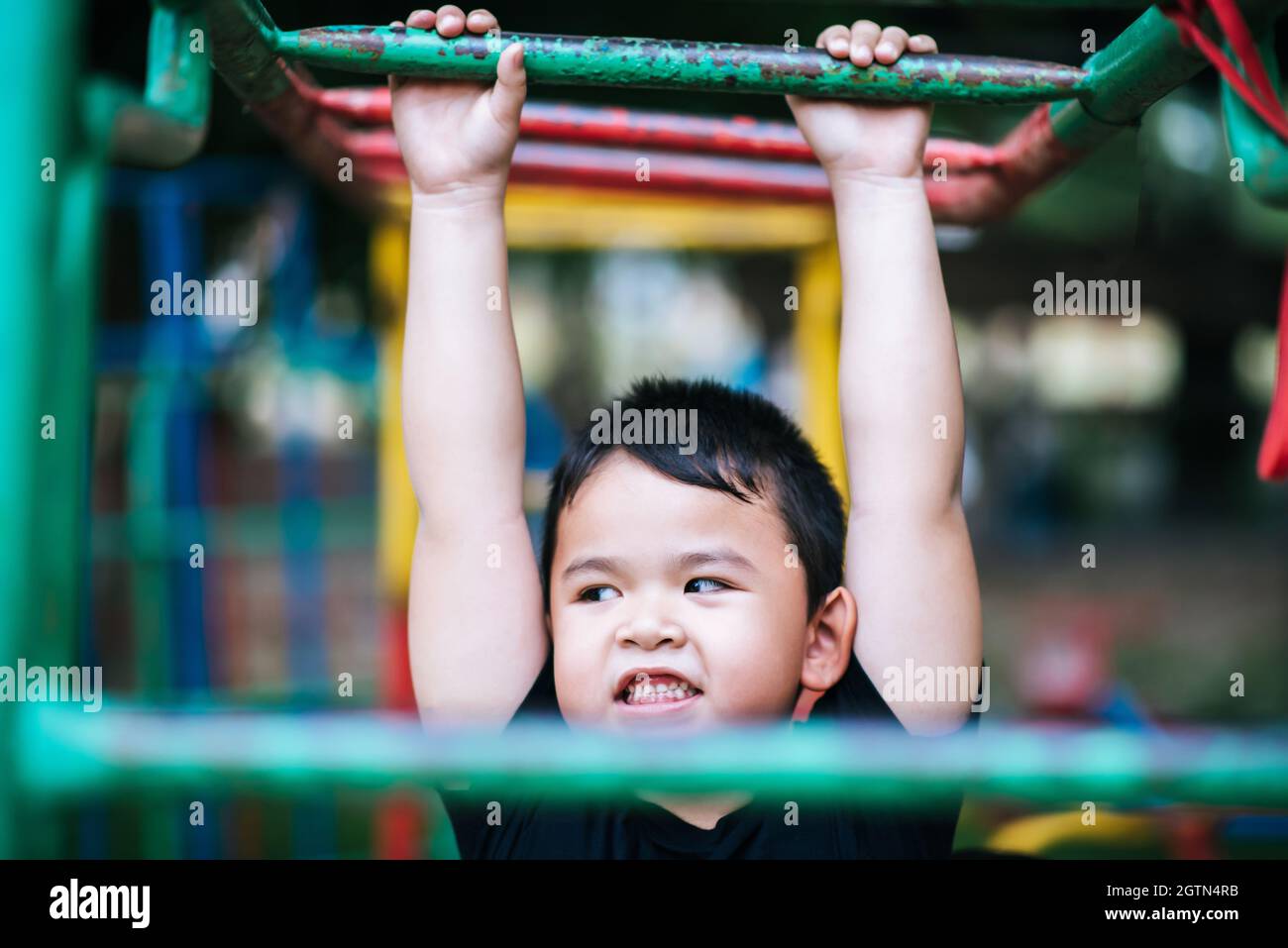 Playful Boy Hanging From Monkey Bars At Playground Stock Photo Alamy