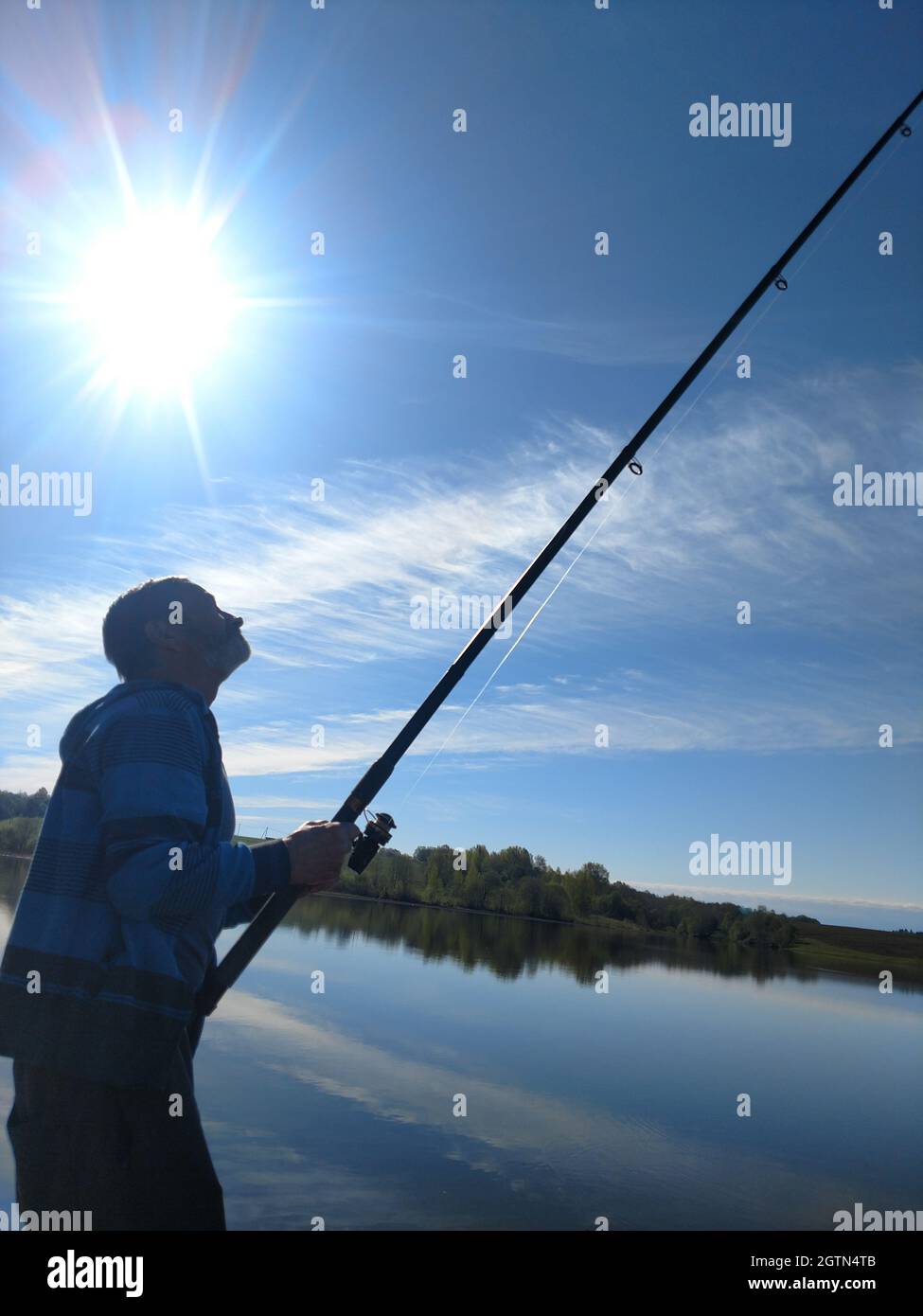 Side View Of Man Fishing In Lake Against Sky Stock Photo