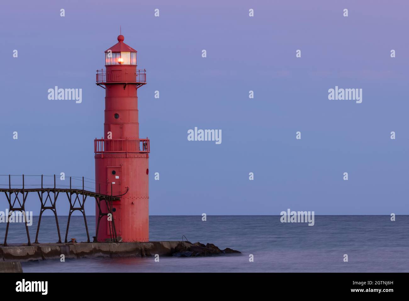 A Red Breakwater Lighthouse Illuminated At Night Along Lake Michigan Stock Photo
