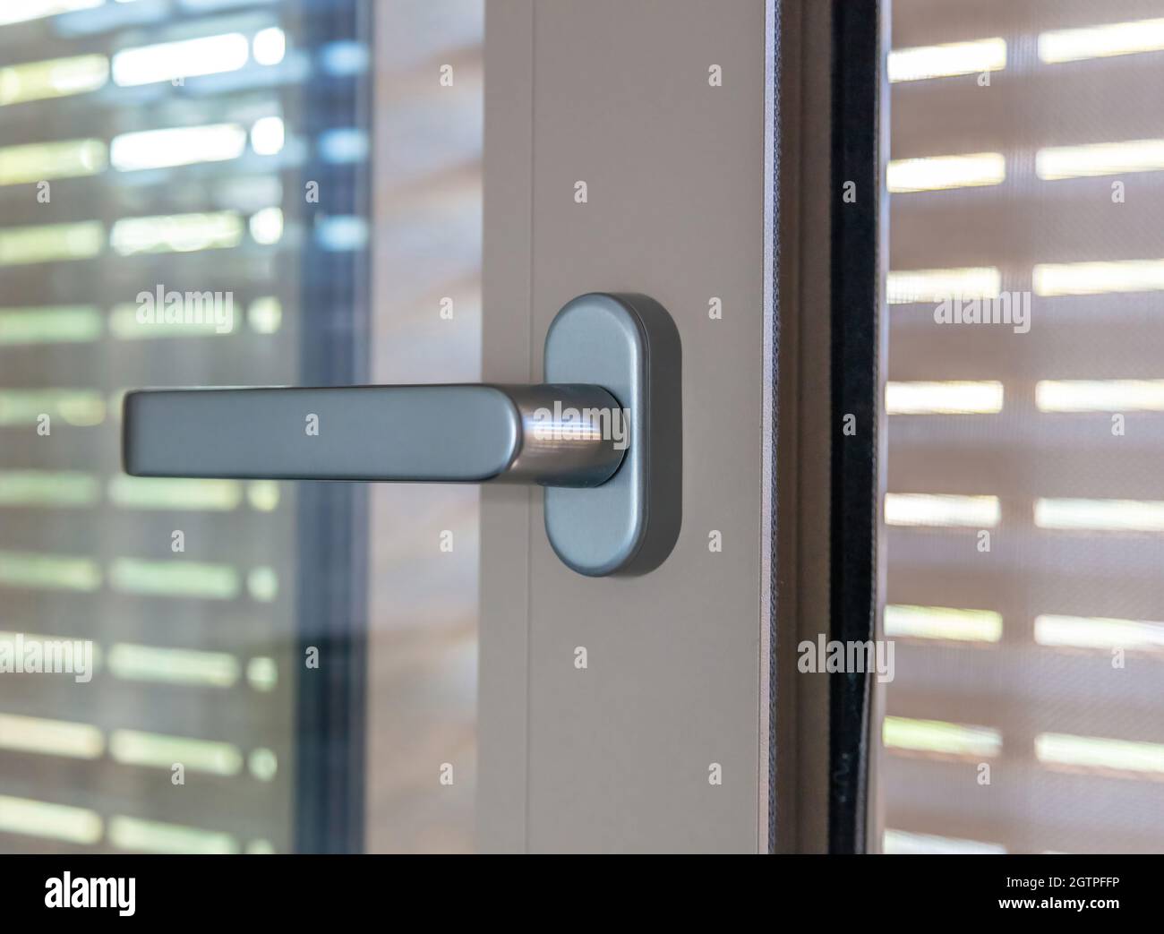 Aluminum window detail. Open steel or plastic glazed door frame and blinds, handle closeup view. Stock Photo
