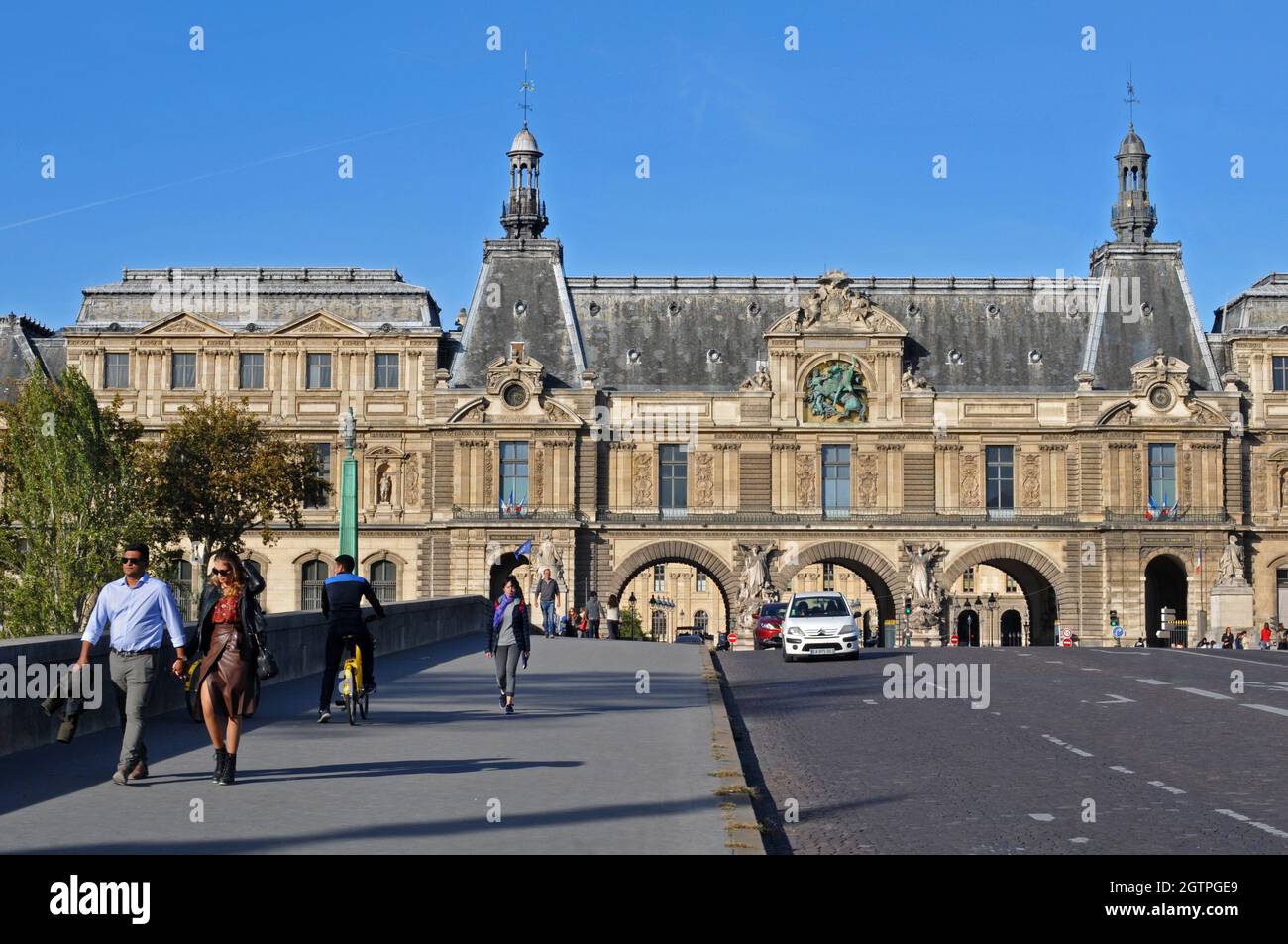 Pedestrians and traffic cross the Pont du Carrousel in front of the historic Pavillon de la trémoille, part of the Louvre complex. Stock Photo