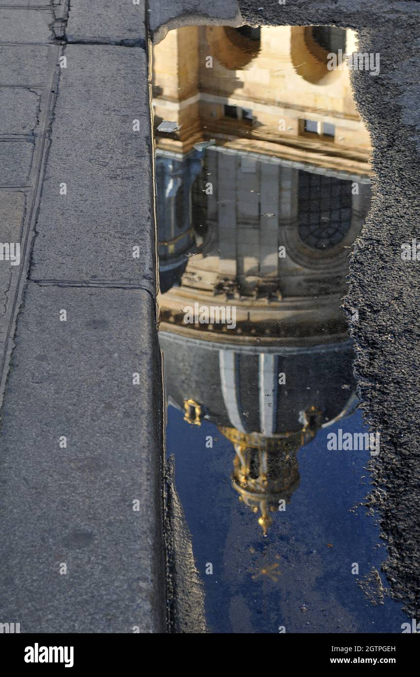 The dome of the Institut de France is reflected in a puddle on a Paris street. The building originially housed the Collège des Quatre-Nations. Stock Photo