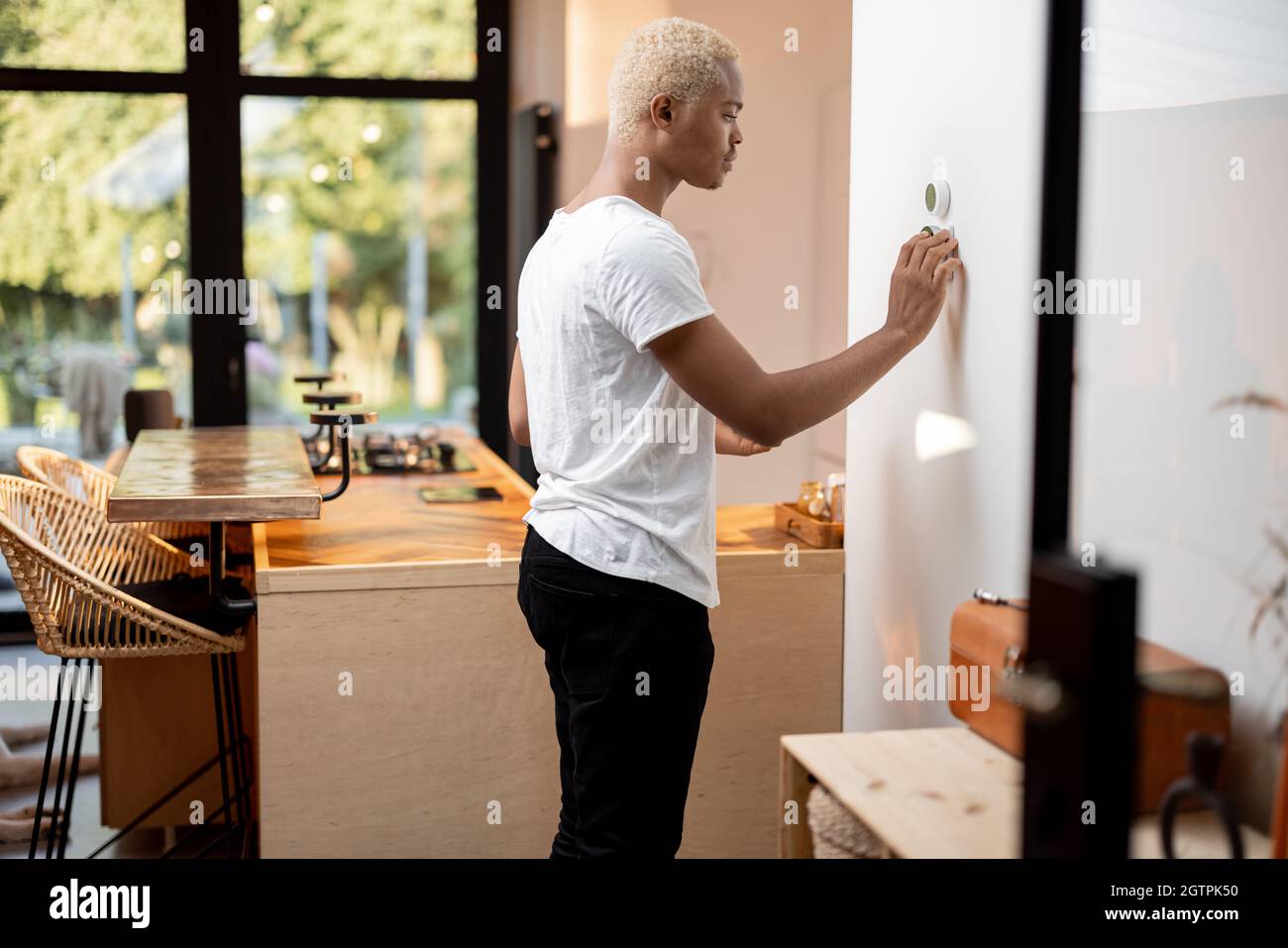Black man choosing temperature on thermostat Stock Photo