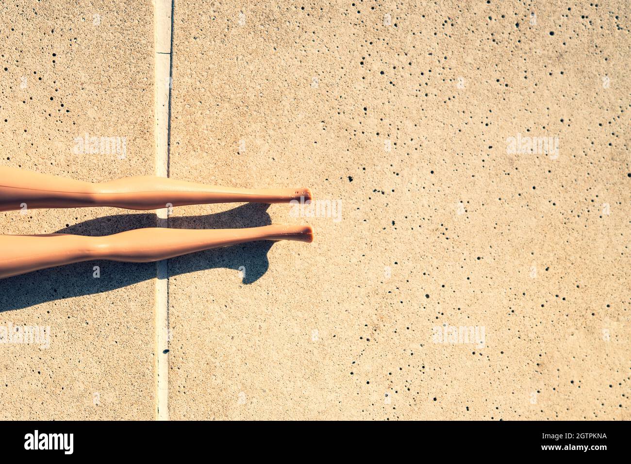 Directly Above Shot Of Cropped Doll On Footpath During Sunny Day Stock Photo