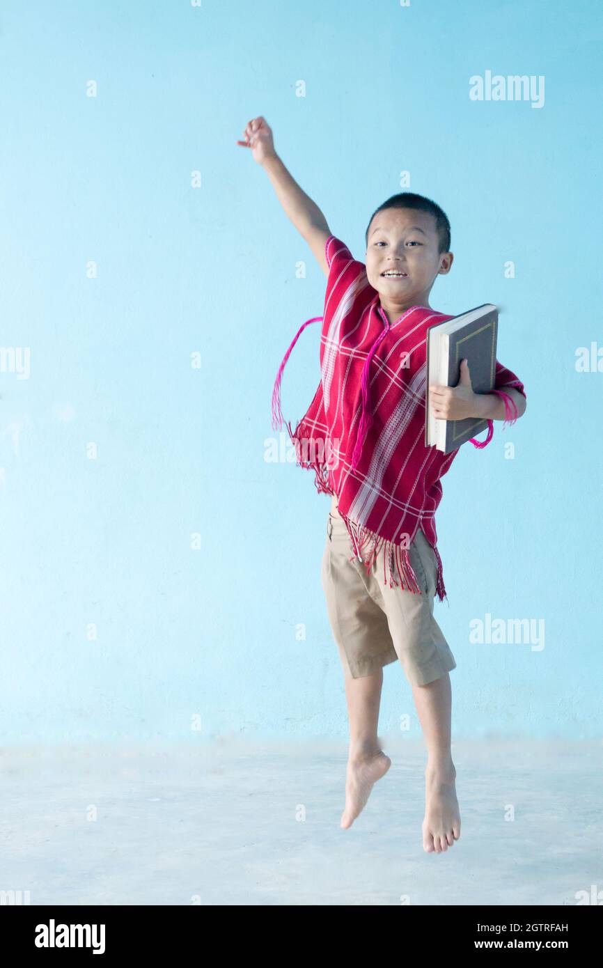 Boy Holding Book While Standing Against Blue Background Stock Photo