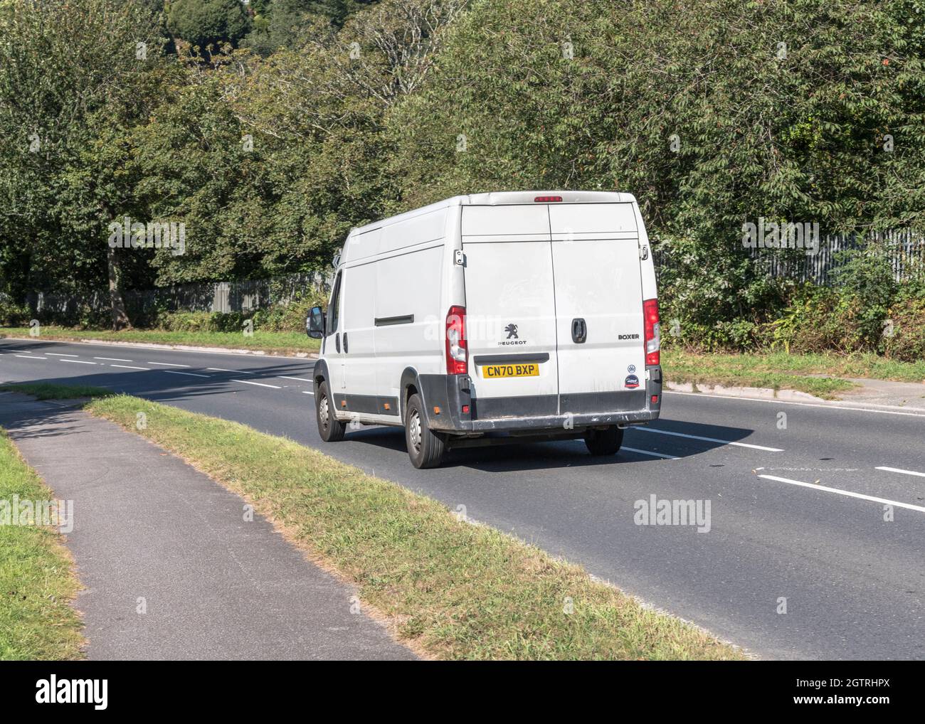 Unmarked white Peugeot delivery van going downhill on country road. For UK driver shortage, goods delivery during Covid, UK transport Stock Photo