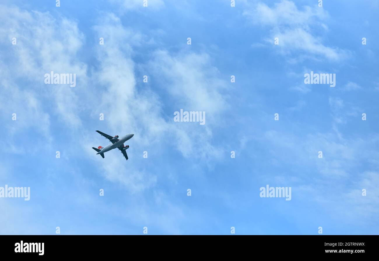 The plane flies in the evening blue sky with clouds Stock Photo - Alamy