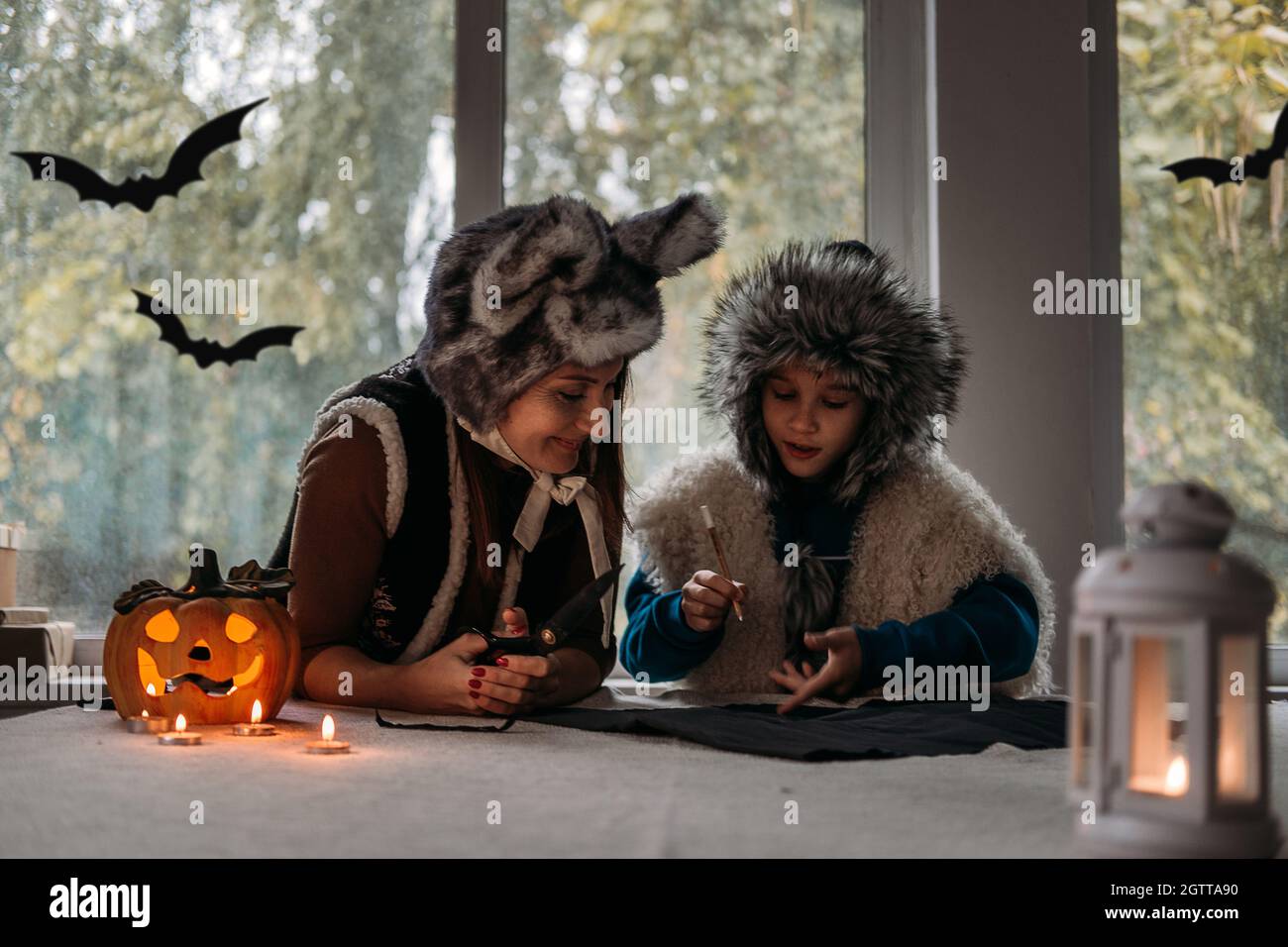 Mom and son in Halloween costumes play together and make paper bat Halloween  decorations on pumpkins lamp at home backgound. Halloween family at home  Stock Photo - Alamy