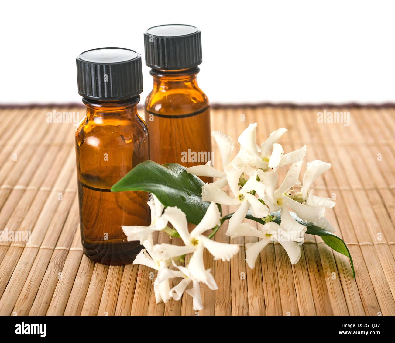 Close-up Of Bottles With White Flowers Over White Background Stock Photo