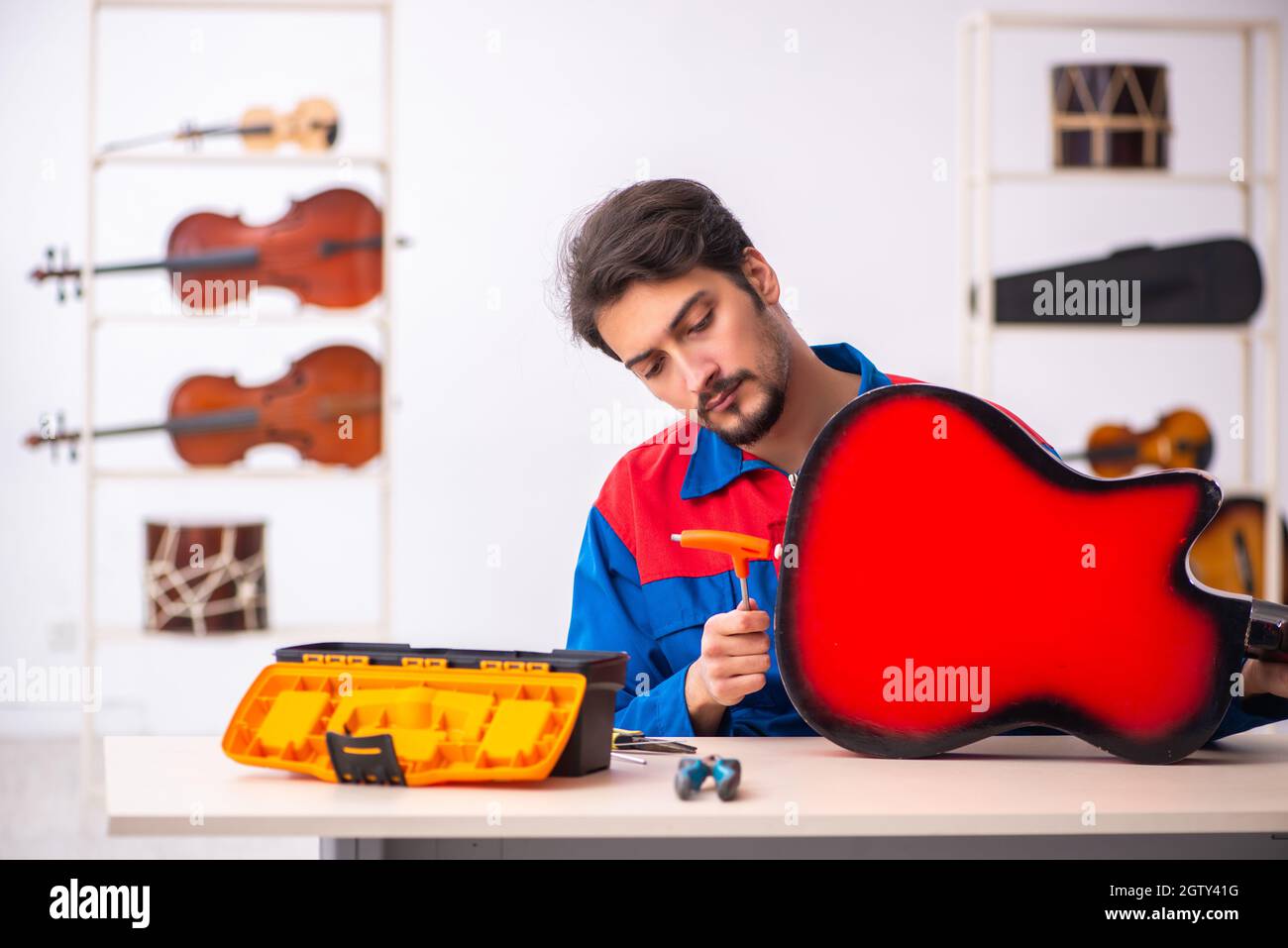 Young repairman repairing musical instruments at workplace Stock Photo