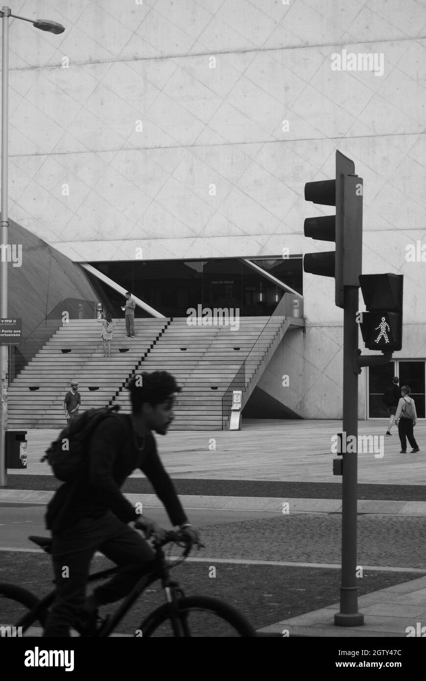 Urban lifestyle in monochrome - Modern building and a cyclist passing by in a blur, a traffic light and city road - Black and white street photo Stock Photo