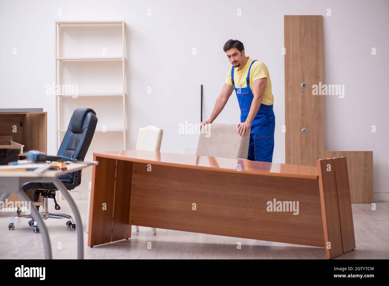 Young carpenter repairing desk in the office Stock Photo Alamy